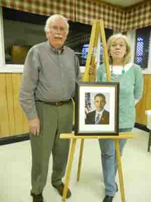 Kerry Sipe, publicity chair, and Chris Carr, historian, unveil the portrait of the president the club hopes will be displayed in the Presidents Room at the LOW Clubhouse.